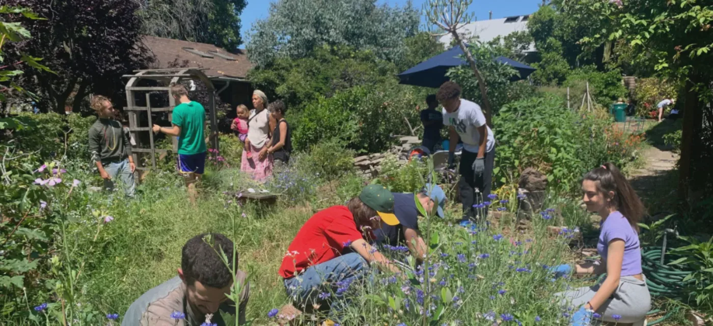 Volunteers of many ages and backgrounds tending flowering garden beds together at Canticle Farm in Oakland