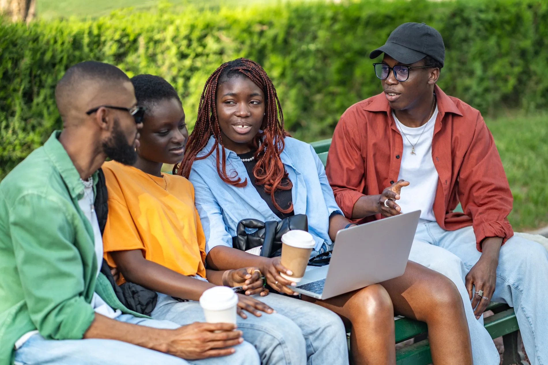 Four young people working together on a laptop outdoors