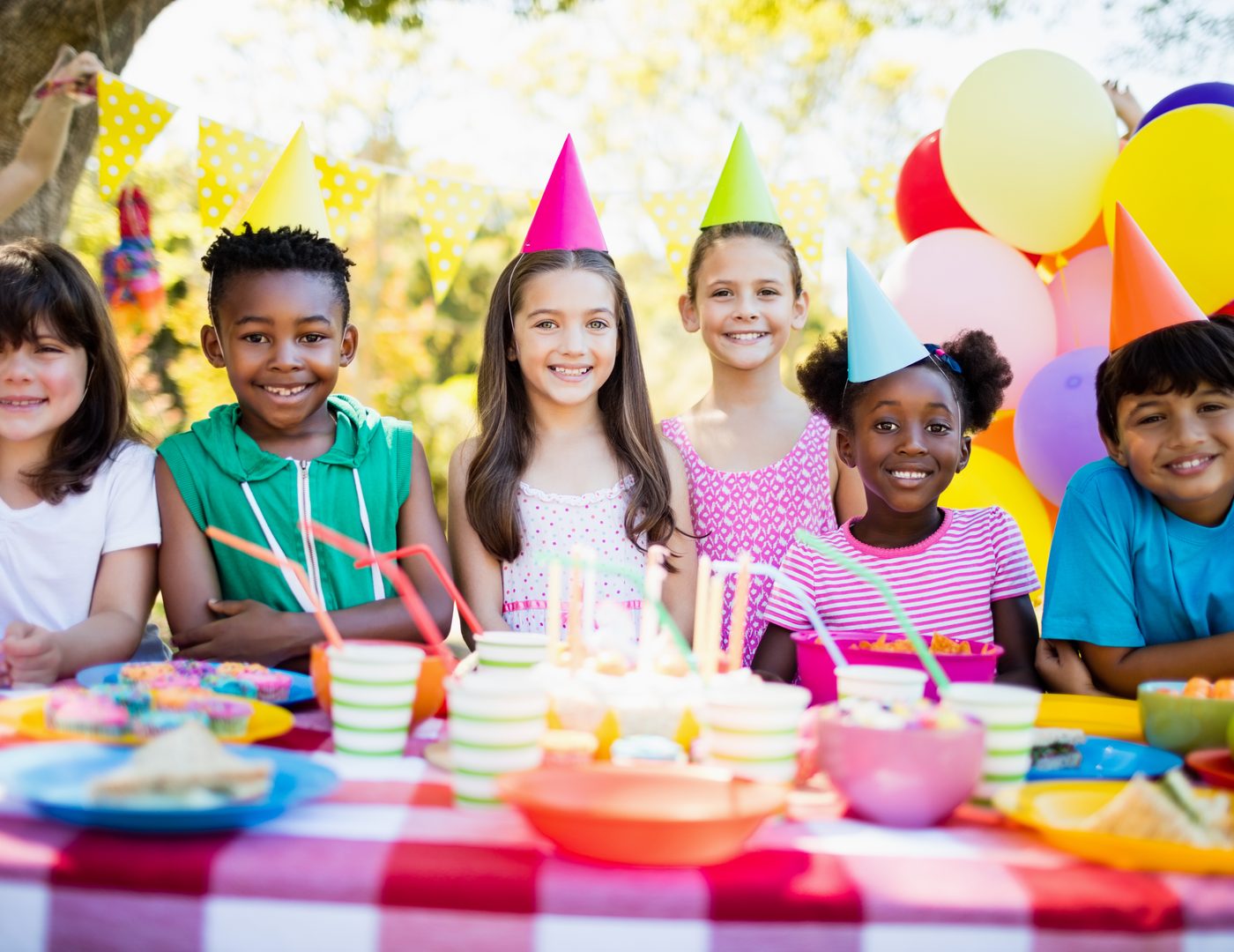 Children in party hats smiling together at a birthday celebration
